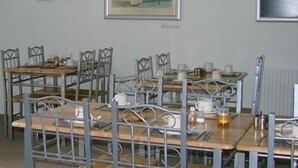 A dining area with metal chairs and tables, framed artwork on the walls, and a menu on the left. - Grand Hastings (St Leonards-On-Sea)
