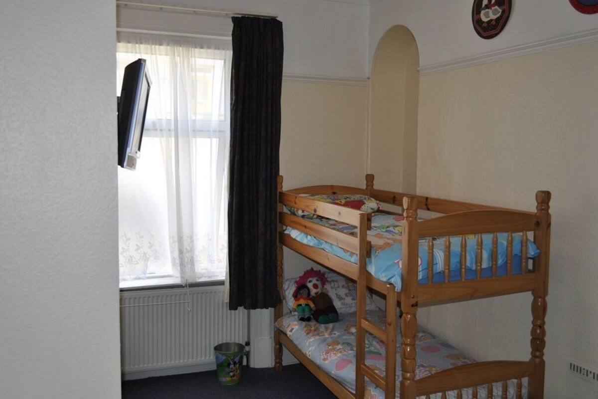 A bunk bed with a window and curtains, a radiator, and a wall with a circular emblem.