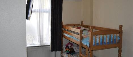 A bunk bed with a window and curtains, a radiator, and a wall with a circular emblem.