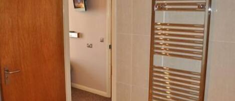 Un baño con un perchero de madera, una puerta y una lámpara de pared.