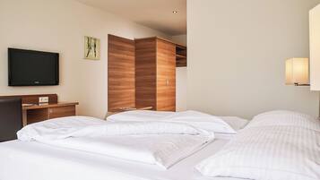 Ein Hotelzimmer mit Bett, Flachbildfernseher, Holzschrank und Nachttischlampe.