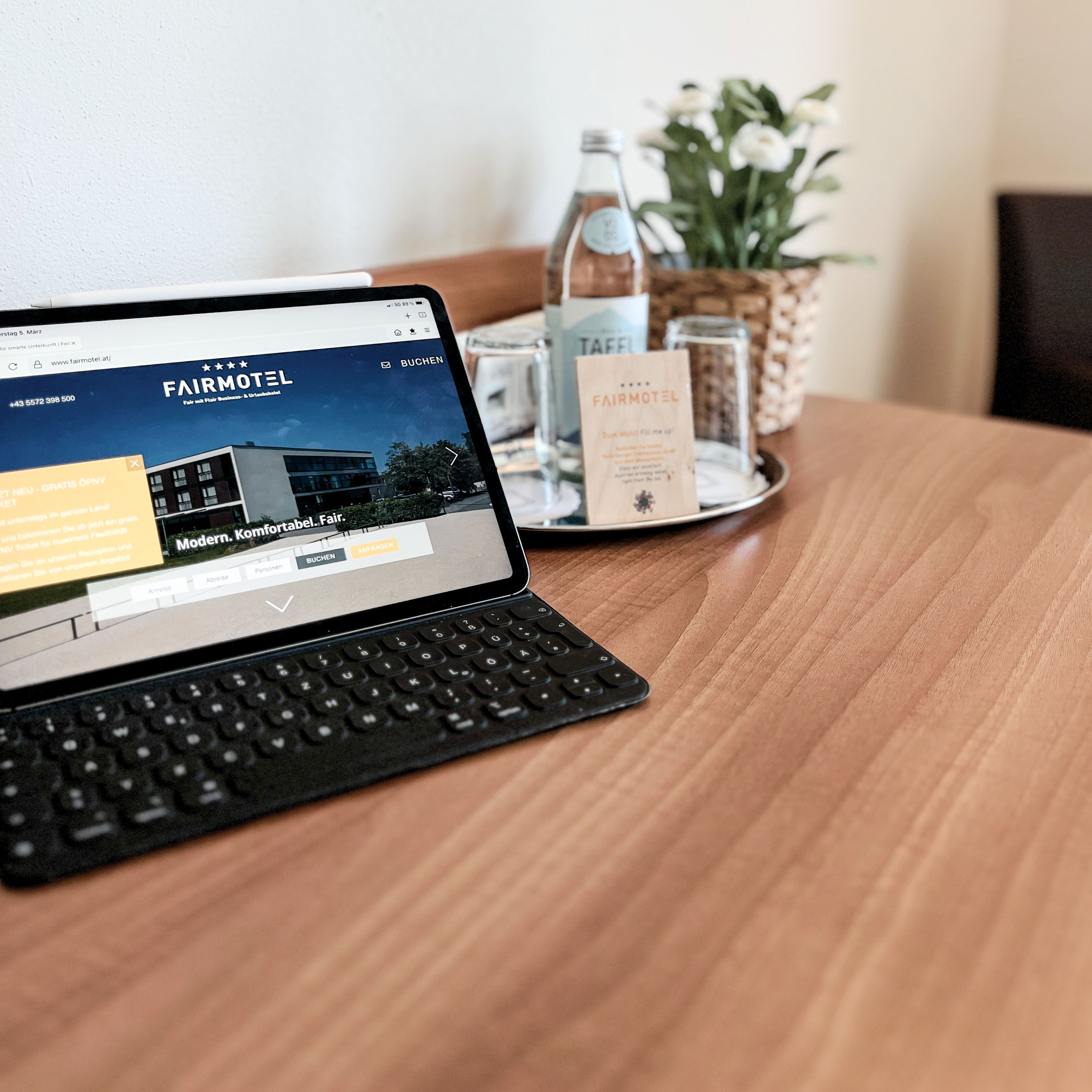 Ein Laptop zeigt eine Webseite für Fair Motel, im Hintergrund ein modernes Gebäude.