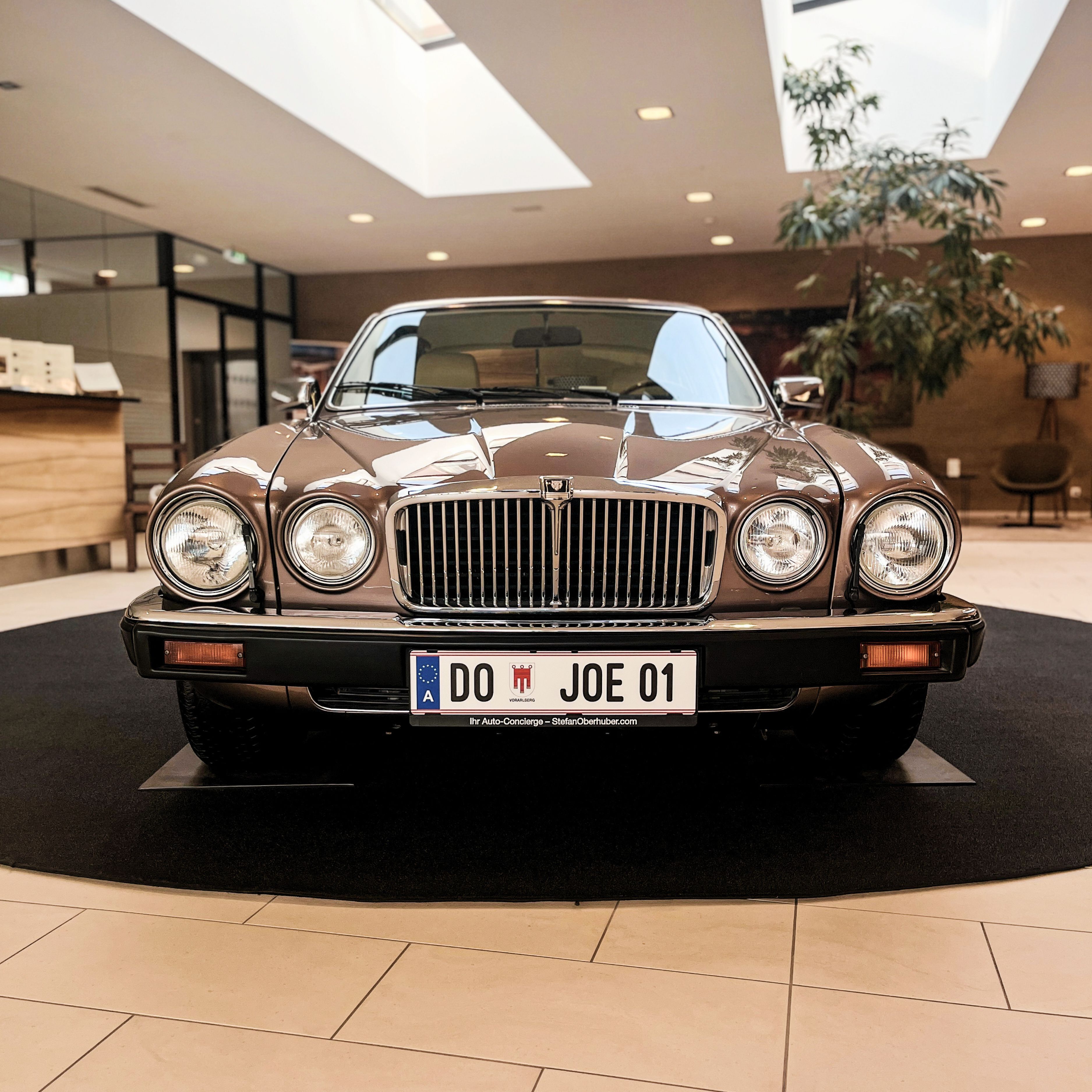 A classic car with a license plate in a modern indoor setting.