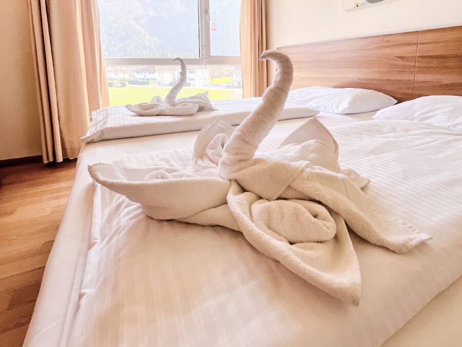Una habitación de hotel con una cama, una ventana con cortinas y vistas a las montañas.