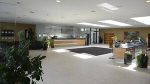 Un espace d’accueil moderne comprenant un comptoir de réception, un coin salon et un îlot de cuisine.