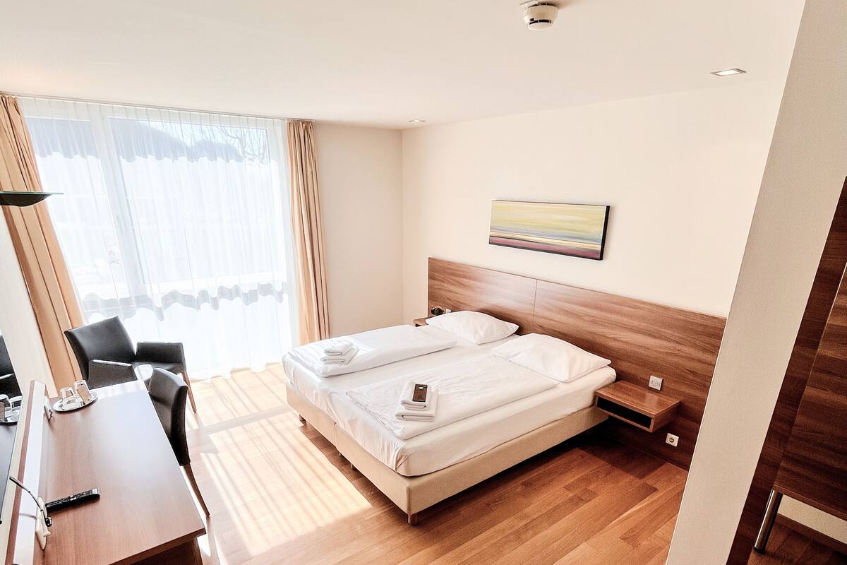 Een hotelkamer met een bed, een bureau en een stoel.