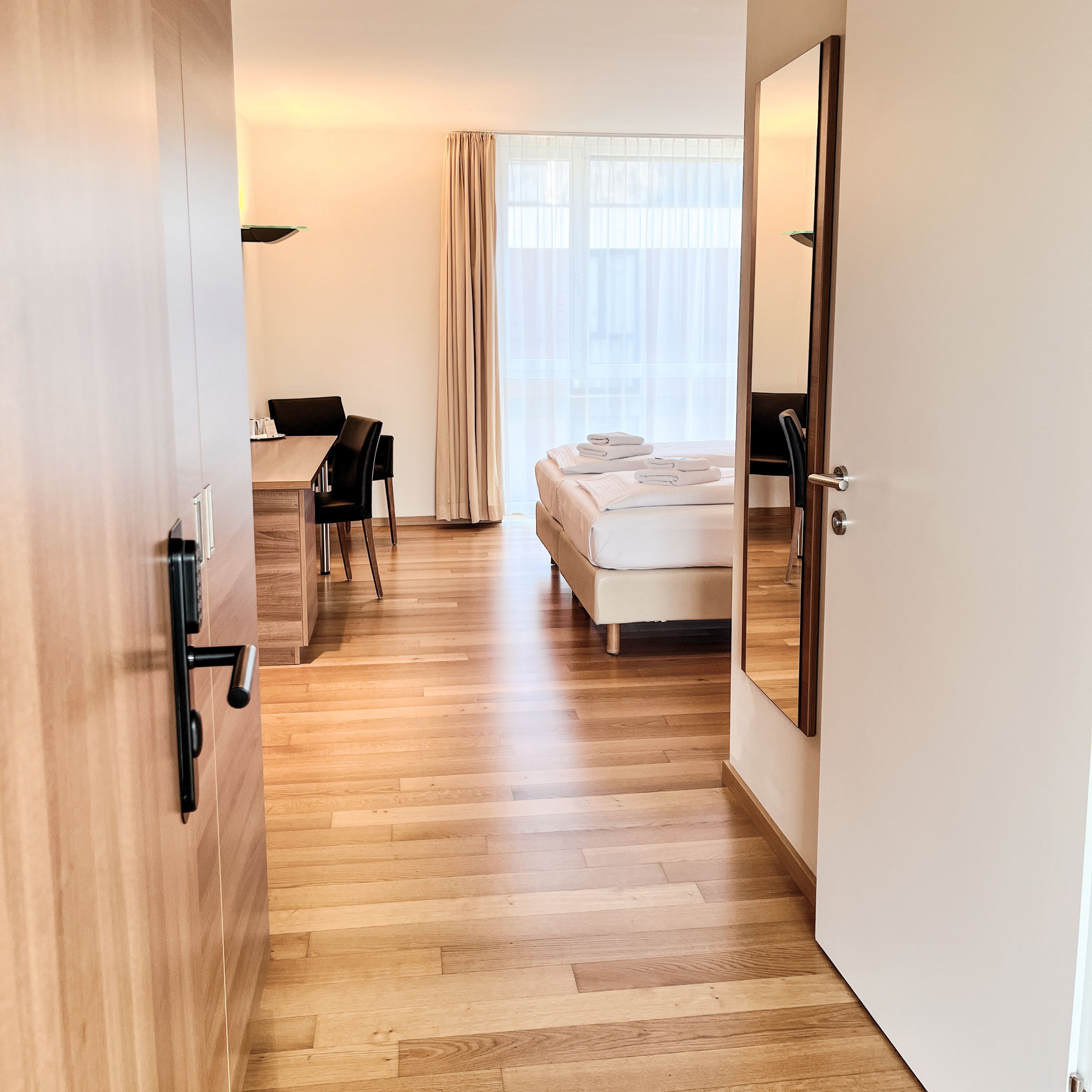 Ein Hotelzimmer mit Holzboden, einem Bett, einem Schreibtisch und einem Stuhl.