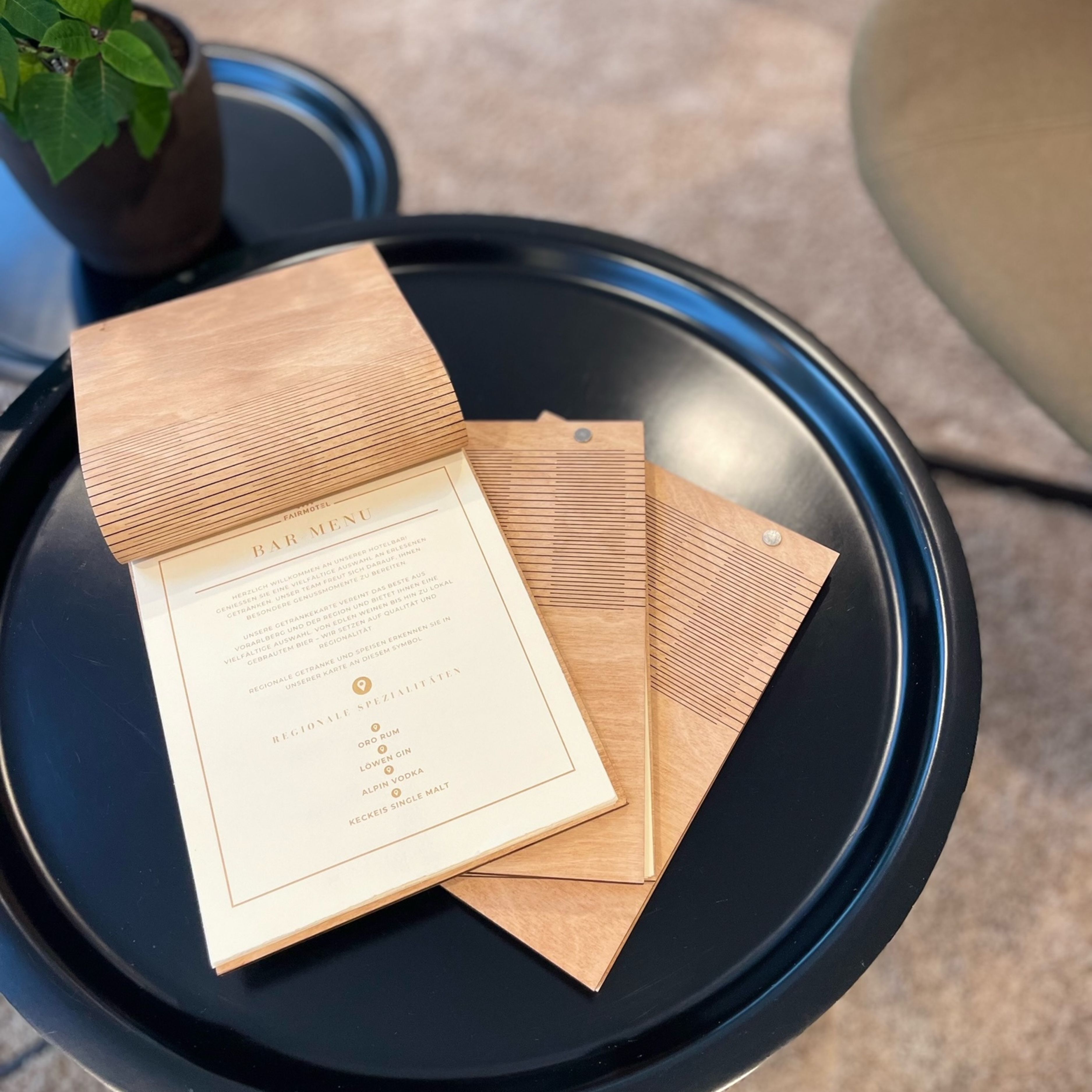 Un menu au design en bois, posé sur un plateau noir.