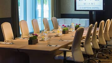 A conference room with a long table, chairs, and a screen displaying hotel branding.