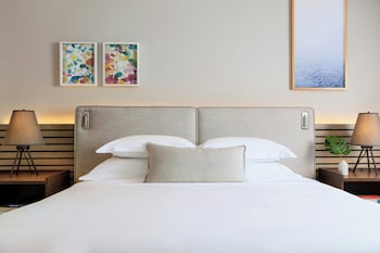 A modern living room with a view of a city skyline, a round table with a vase and books, and two armchairs. at Kimpton EPIC Hotel by IHG