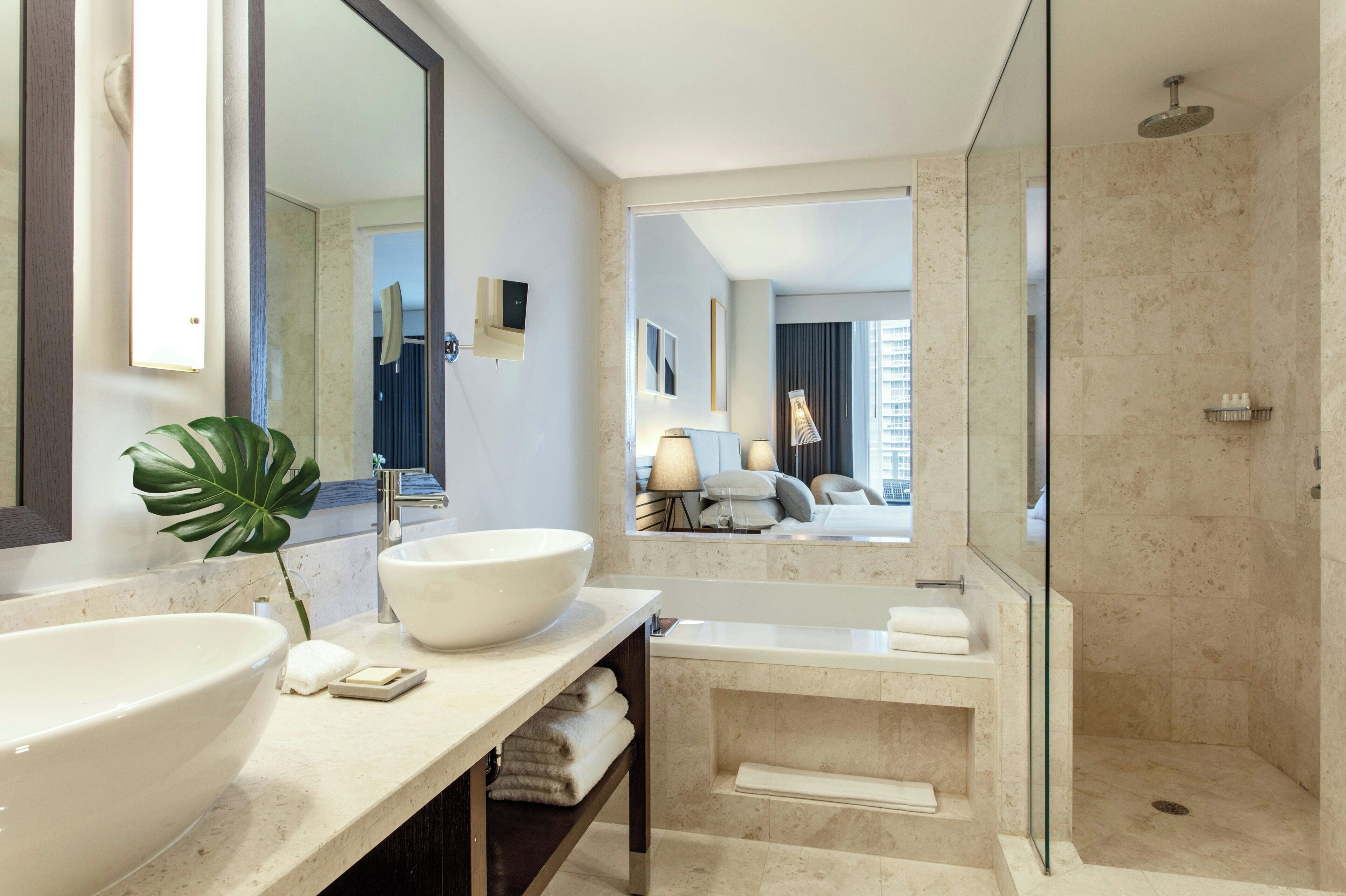 Un baño moderno con un espejo grande, un lavabo, una bañera y una ducha.
