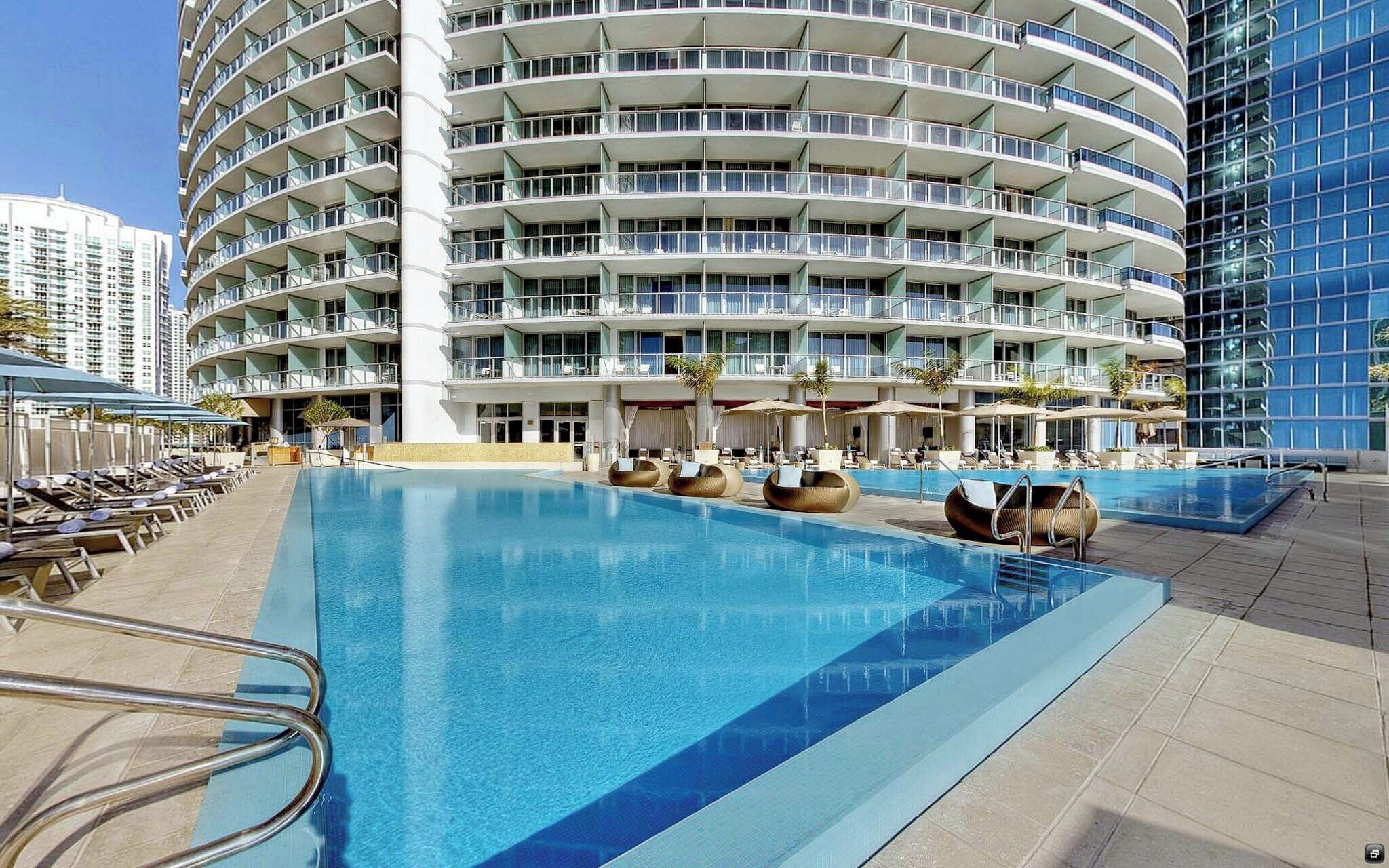 Un hôtel doté d’une grande piscine extérieure, de nombreux balcons et de chaises longues.