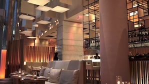 A modern interior with high ceilings, recessed lighting, and a bar area with shelves of bottles. - Kimpton EPIC Hotel by IHG (Miami)
