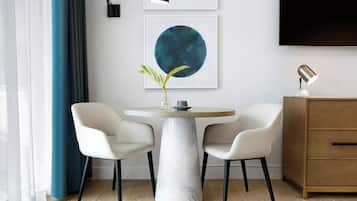 A modern dining area with a marble table, two chairs, a vase with a plant, and artwork on the wall.