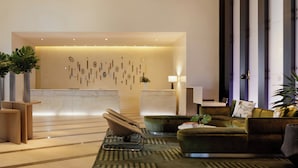 Un vestíbulo moderno con una recepción, un área de descanso y arte decorativo en la pared.