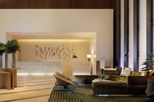 A modern lobby with a reception desk, seating area, and decorative wall art.