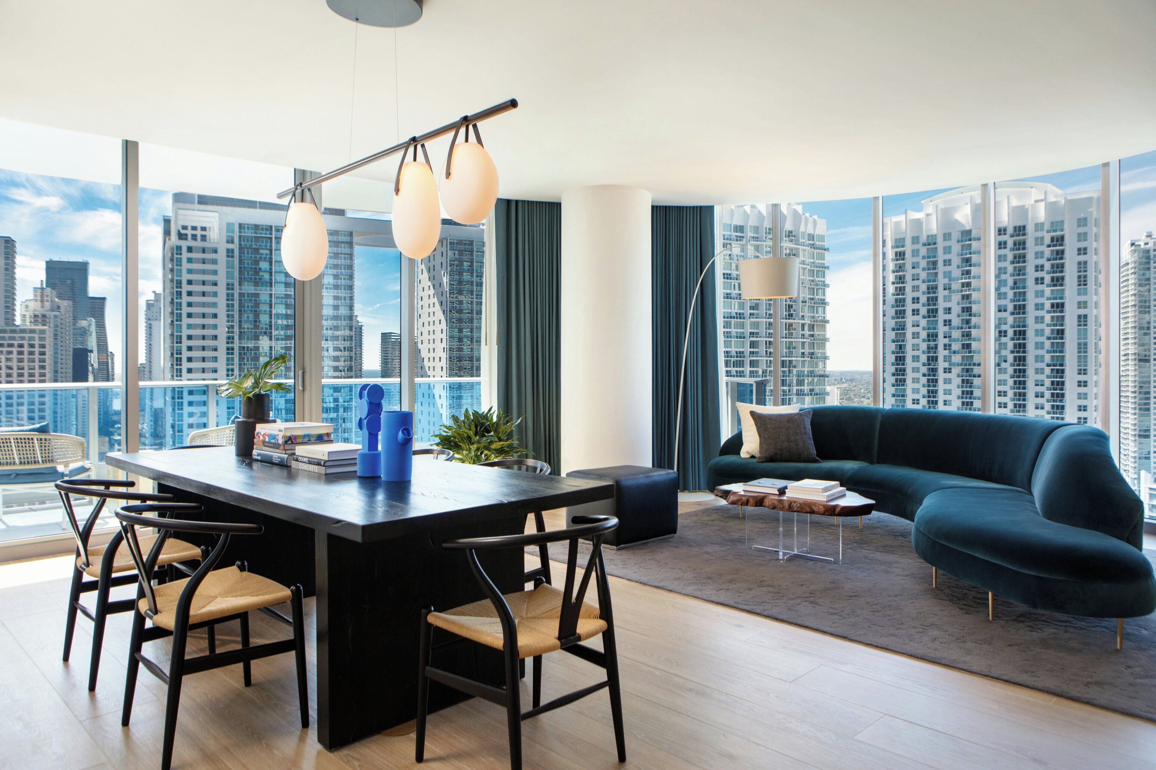 A modern living room with a dining area, large windows, and a city view.