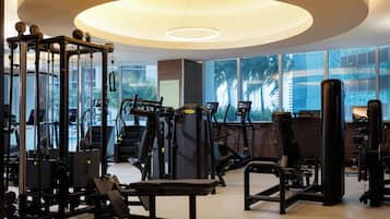 A gym with various exercise equipment, large windows, and a modern ceiling design.