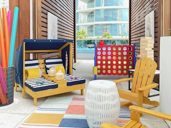 A balcony with two wicker chairs and a small wooden table, overlooking a cityscape with high-rise buildings. at Kimpton EPIC Hotel by IHG