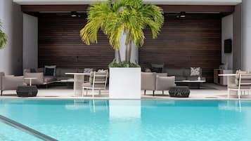 Uma área à beira da piscina com assentos, piscina e um painel de parede de madeira.
