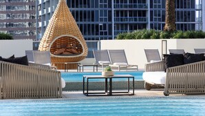 A poolside area with lounge chairs, a small table, and a unique conical seating area. - Kimpton EPIC Hotel by IHG (Miami)