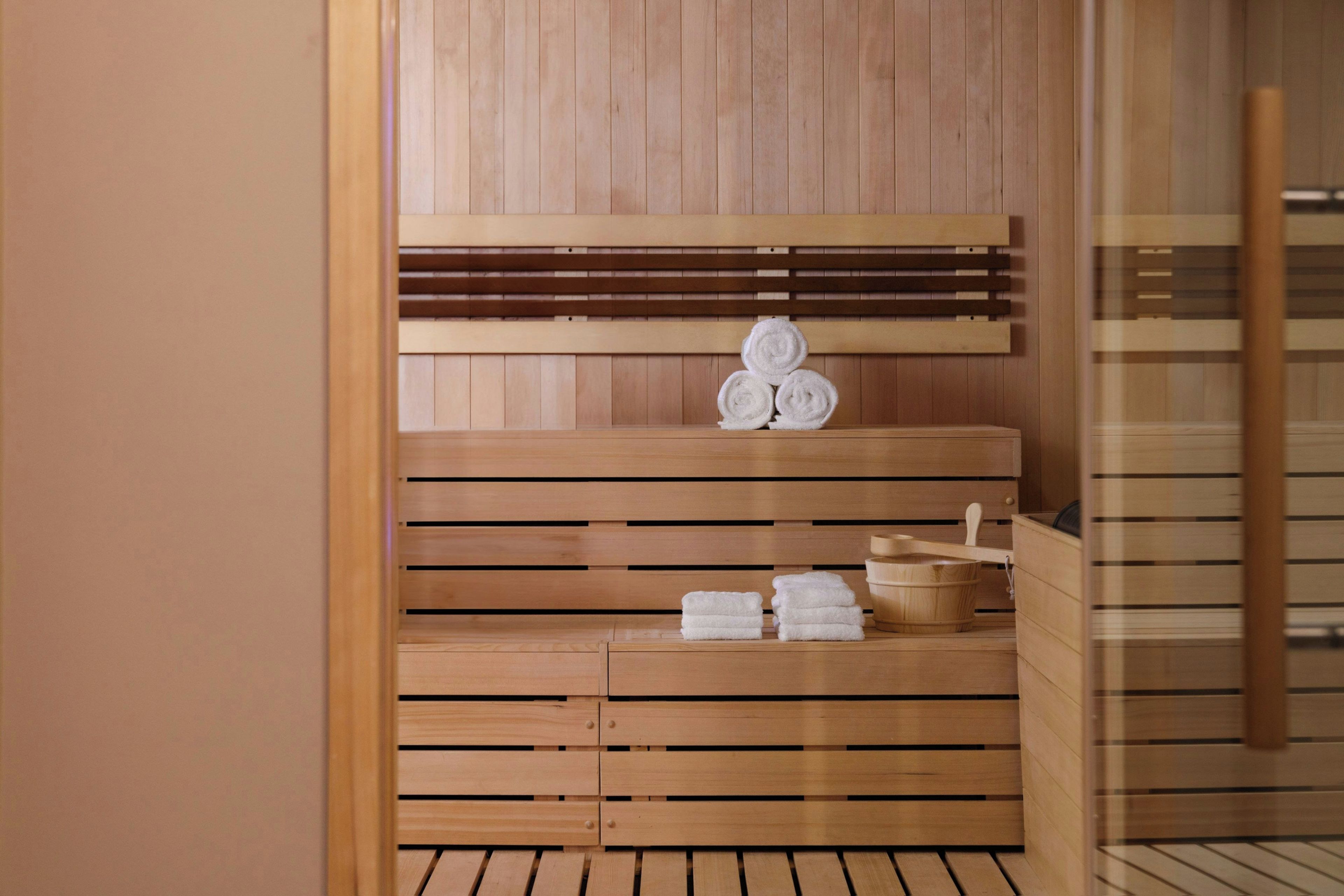 A sauna with wooden benches and a shelf holding towels.