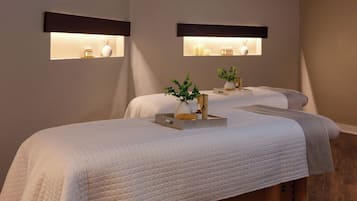 Une chambre d’hôtel avec deux lits, chacun étant doté d’une table de chevet, d’un vase et d’une bouteille.