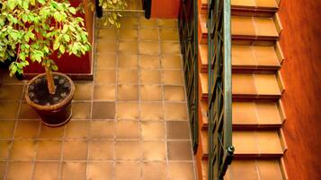 A tiled patio with a small table and two chairs, a potted plant, and a staircase with a metal railing.