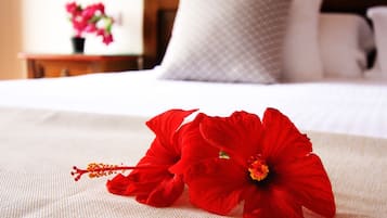Un lit recouvert d’une courtepointe blanche et orné de deux fleurs d’hibiscus rouges.