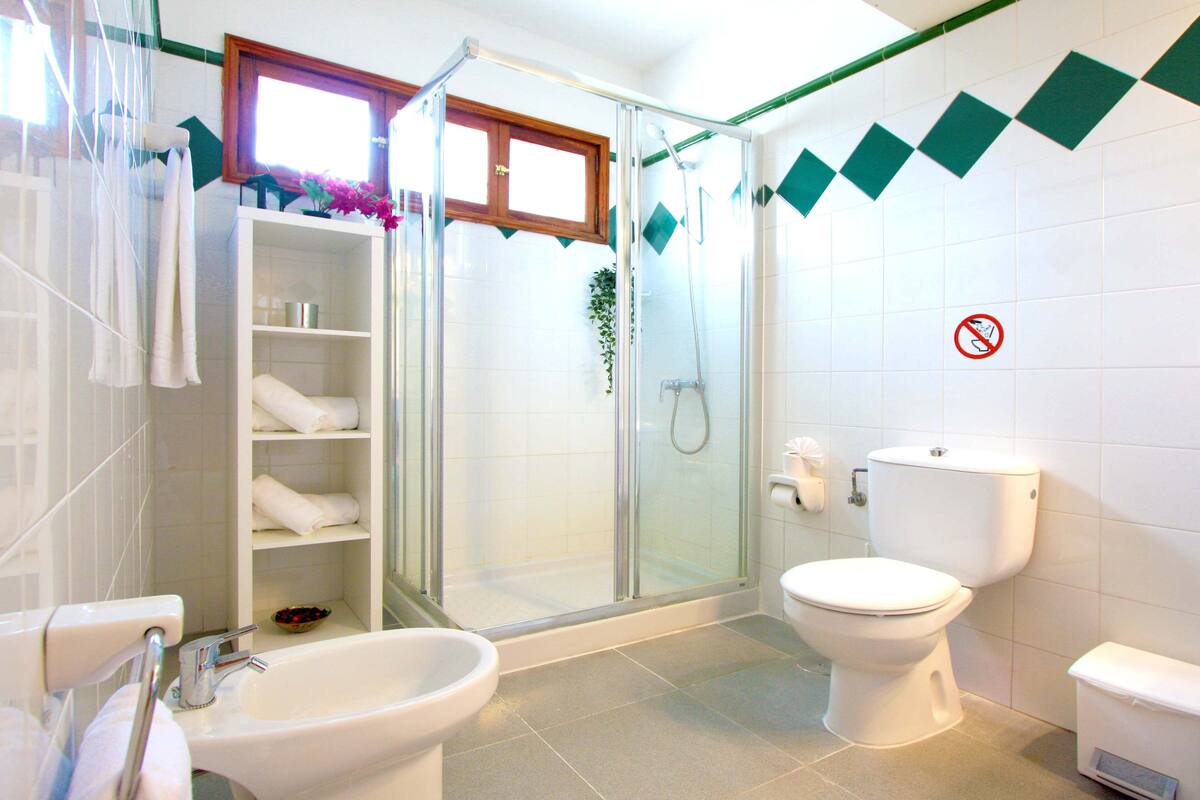 A bathroom with a glass-enclosed shower, a toilet, and a sink.
