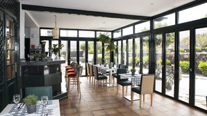 A restaurant with a terrace, tables set for dining, and a bar area with a counter and seating. - Hotel Rural Finca de la Florida (San Bartolome)