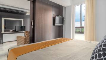 Una habitación de hotel moderna con una cama grande, un televisor de pantalla plana montado en la pared, un sofá y un balcón con vistas.