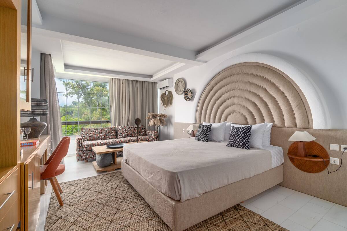 Een moderne slaapkamer met een groot bed, een bank, een bureau en uitzicht op de omgeving.
