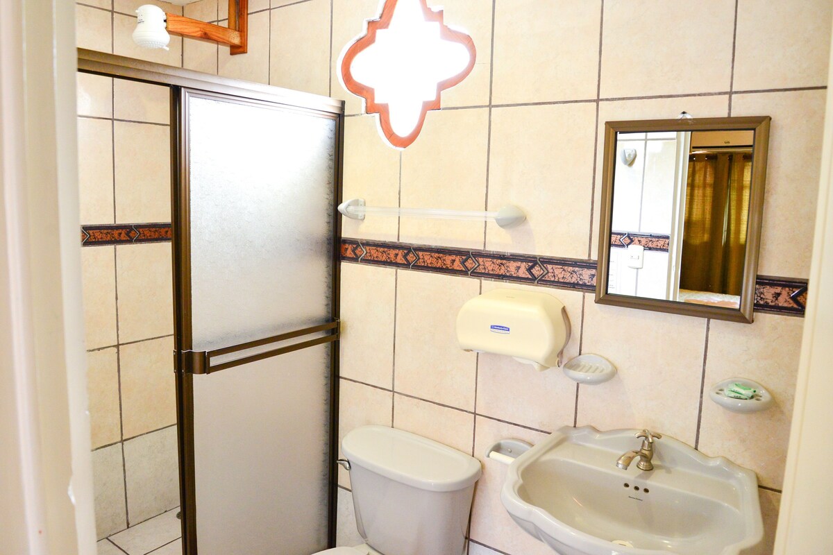 Ein Badezimmer mit Toilette, Waschbecken, Spiegel und einem Händetrockner.