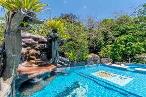 Una piscina al aire libre, sombrillas, sillones reclinables de piscina