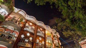 Un hôtel à plusieurs étages doté de balcons, chacun étant agrémenté d’une balustrade blanche et d’un petit espace aménagé en jardin.