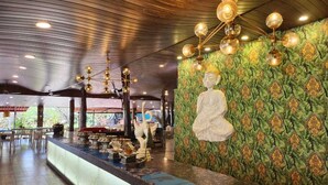 A room with a large Buddha statue, a patterned wall, and a ceiling with hanging lights. - Paradise Village Beach Resort (Calangute)