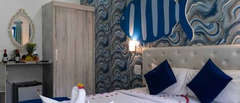 A hotel room with a bed, a wardrobe, a mirror, and a wall with a wavy pattern.