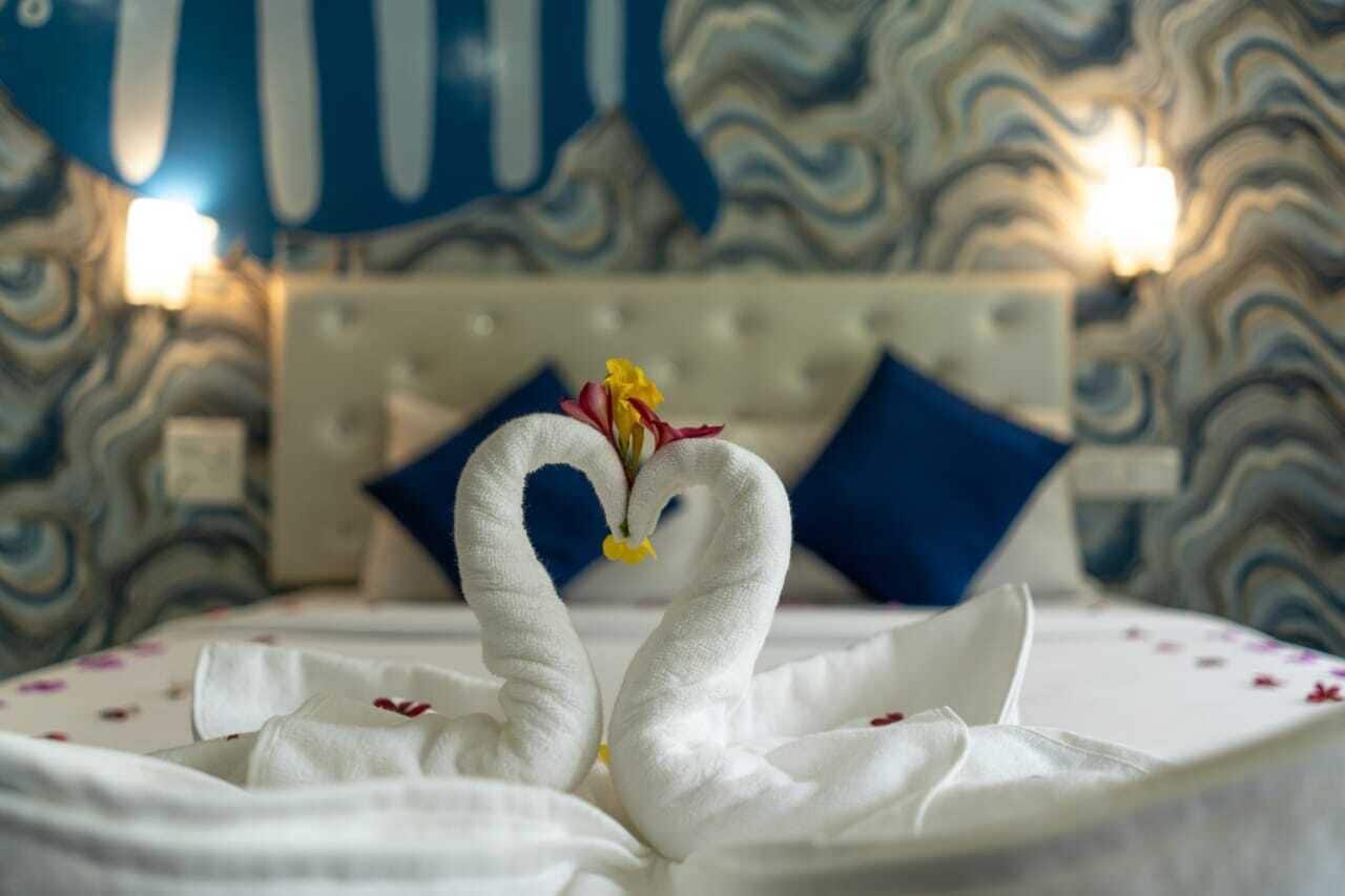 A bed with a decorative swan made of white fabric and a small yellow flower. The bed has a white and red floral bedspread.