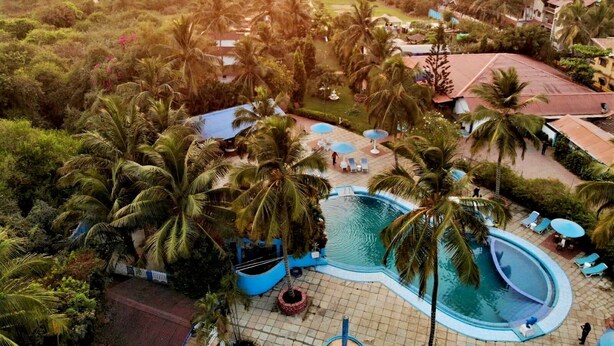 A resort with a pool, palm trees, and a view of the ocean. - Paradise Village Beach Resort (Calangute)