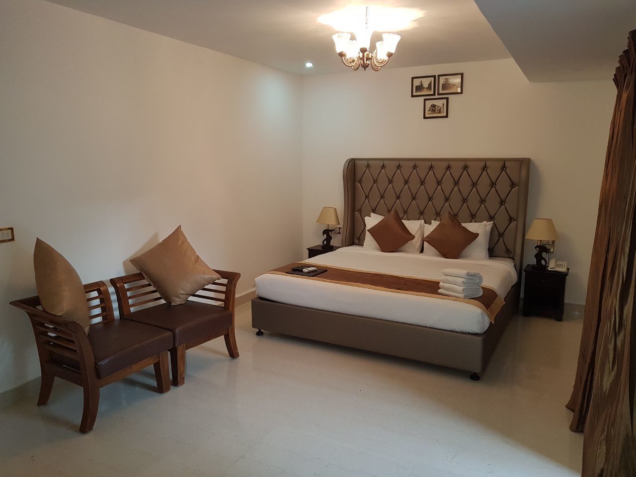 A bedroom with a large bed, a wooden sofa, and two bedside tables with lamps.