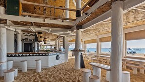 A beachside bar with wooden stools and a bar counter, large windows overlooking the beach. - Beachcomber Island Resort (Beachcomber Island)