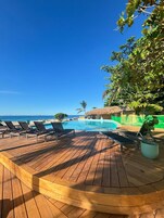 Una piscina al aire libre, sombrillas, sillones reclinables de piscina