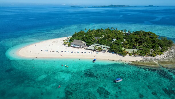 An aerial view of a tropical island with a beach, a resort building, and clear blue waters. - Beachcomber Island Resort (Beachcomber Island)