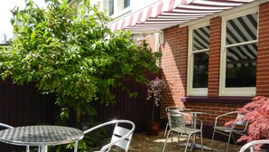 A patio with stone flooring, metal chairs, and a table. - Overcombe House (Yelverton)