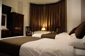 A hotel room with two beds, a desk, a lamp, and a television. - Crown Lodge Guest House (Reading)