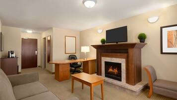 Una sala de estar con chimenea, televisor, escritorio y sofá.