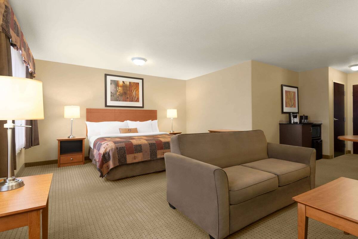 Una habitación de hotel con cama, sofá, escritorio y televisor.