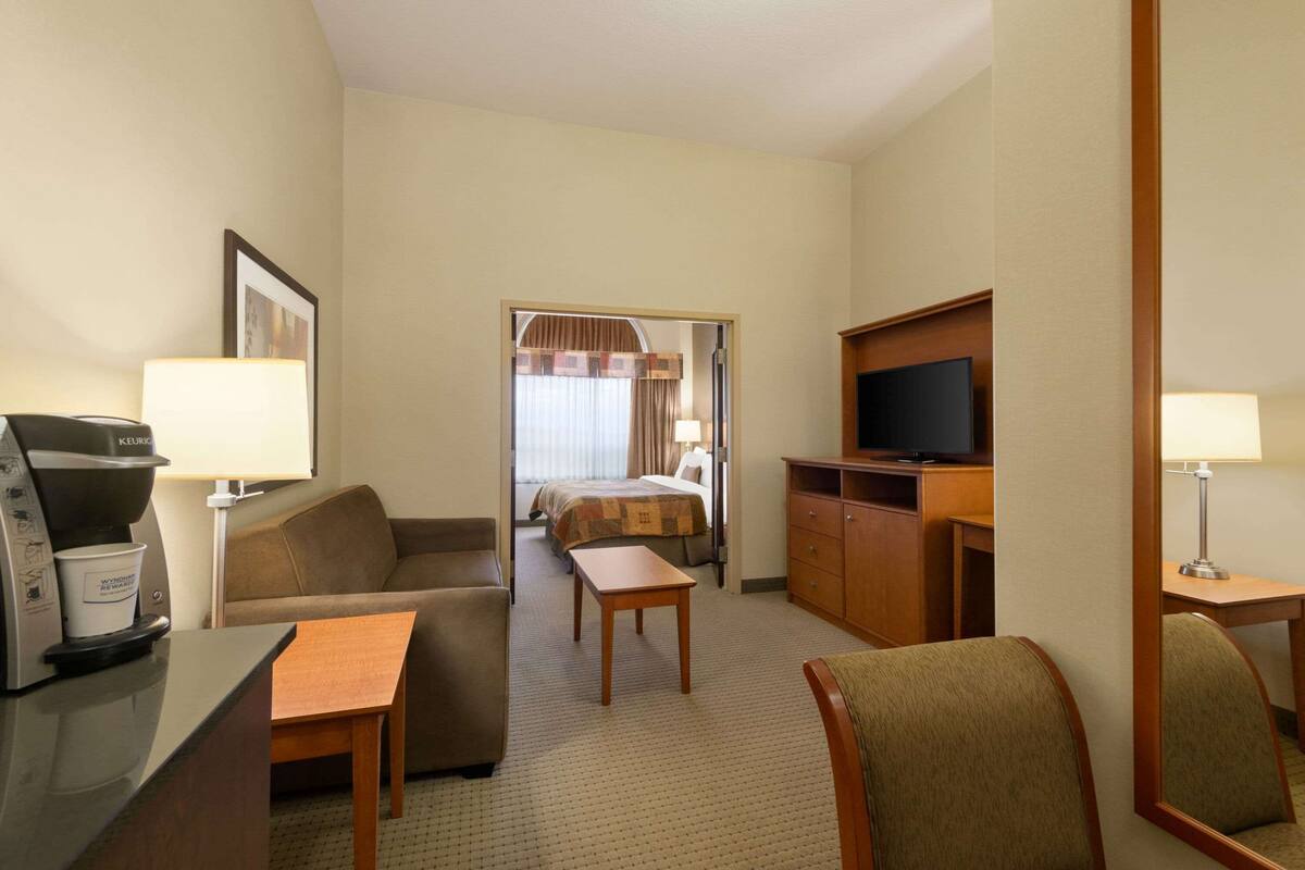 Habitación de hotel con kitchenette, televisión, cama y zona de estar.