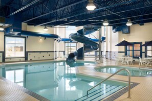 Una piscina interior con tobogán, zona de estar y vistas despejadas al exterior.